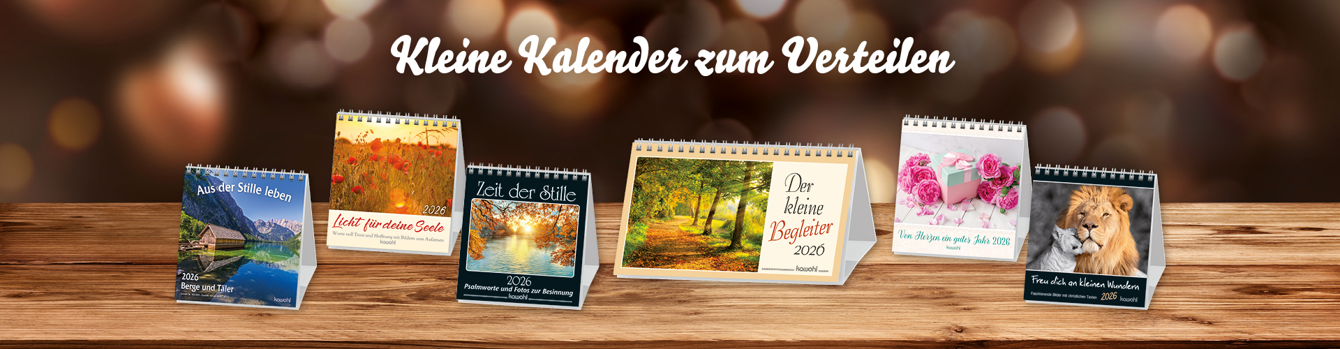 Banner mit verschiedenen kleinen Kalendern für 2026, die auf einem Holztisch präsentiert werden.