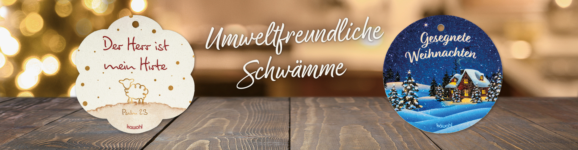 Zwei Pop-Up-Schwämme auf einem Holztisch, mit weihnachtlichem Hintergrund. Text: Umweltfreundliche Schwämme
