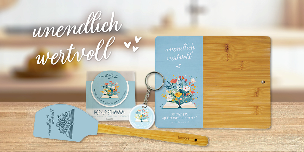Produktkollektion "unendlich wertvoll" mit blauem Teigschaber, Pop-Up-Schwamm, Schlüsselanhänger und Bambus-Brett auf Holztisch.