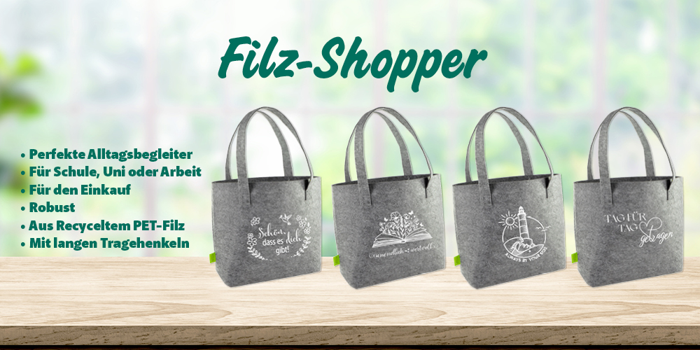 Vier graue Filz-Shopper auf Holztischplatte vor hellem Fensterhintergrund. Auf der rechten Bildseite steht folgender Text: Perfekte Alltagsbegleiter Für Schule, Uni oder Arbeit Für den Einkauf Robust Aus Recyceltem PET-Filz Mit langen Tragehenkeln 