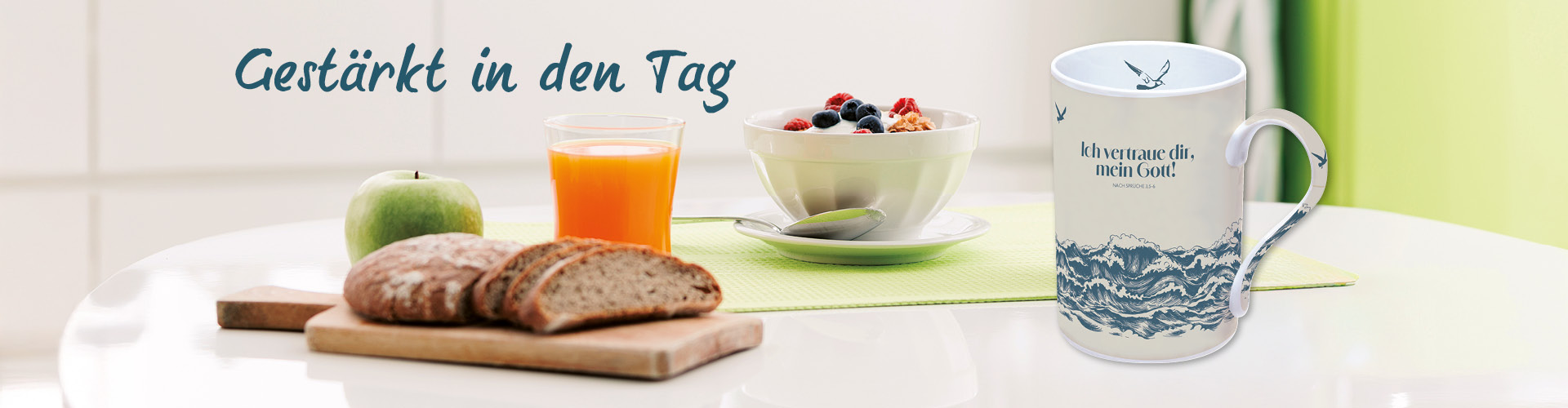 Frühstückstisch mit einer Tasse, einer Müslischale, einem Glas Saft, Brot und einem grünen Apfel. Text: Gestärkt in den Tag.