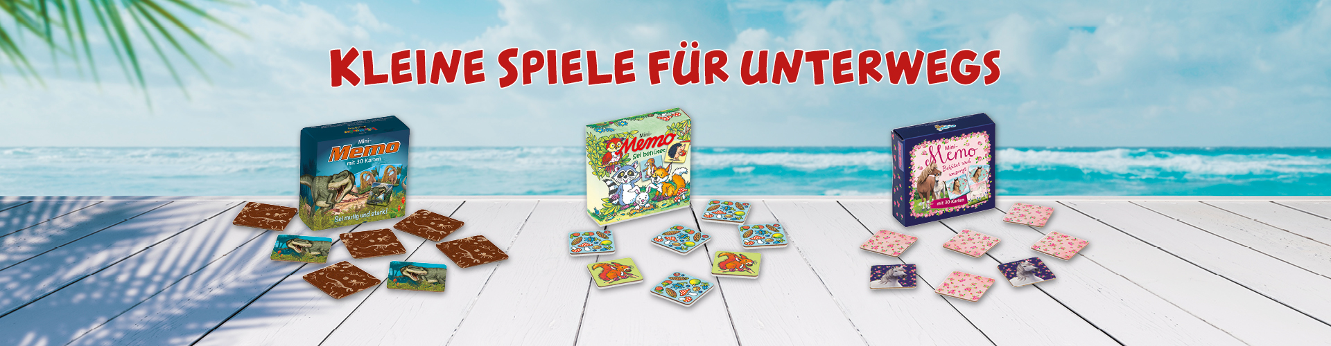 Helle Holzplanken im Vordergrund, tropisches Meer im Hintergrund. Auf Planken stehen drei kleine Memory-Spiele, einmal mit Dinosauriern, mit Waldtieren und mit Pferden.