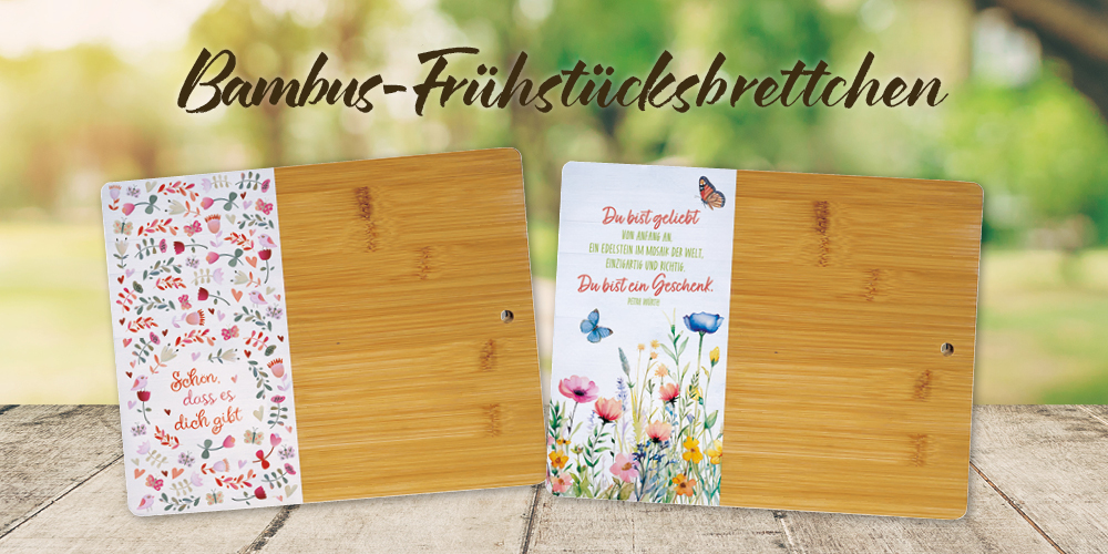 Banner mit einem Holztisch, vor einem grünen Park mit Baum, auf dem Tisch stehen zwei schön dekorierte Bambus-Brettchen. Text: „Frühstücksbrettchen, aus robustem Bambus, mit stilvollem Druck“.