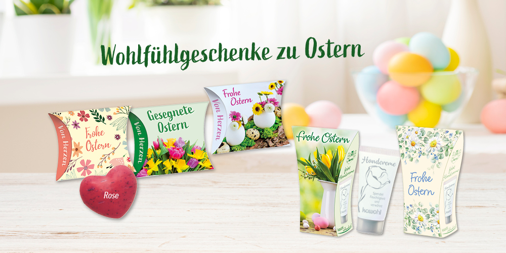 Foto von hellem Raum mit bunten Ostereiern und einer grünen Pflanze im Hintergrund. Verschiedene Handcreme- und Schafmilchseifen-Verpackungen mit Ostergrüßen sind abgebildet, über den Produkten steht der Text: „Wohlfühlgeschenke zu Ostern“.