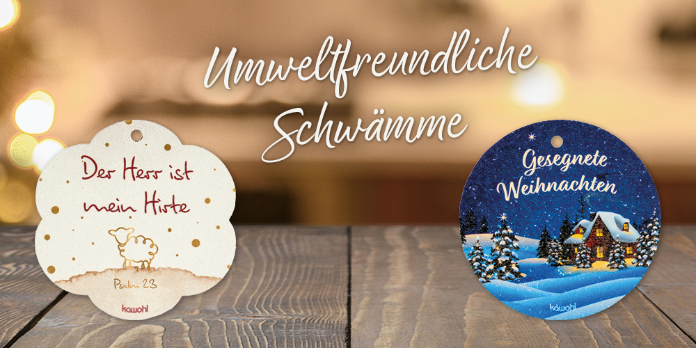 Zwei Pop-Up-Schwämme auf einem Holztisch, mit weihnachtlichem Hintergrund. Text: Umweltfreundliche Schwämme