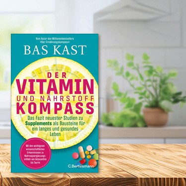 Buchtitel 'Der Vitamin- und Nährstoffkompass' von Bas Kast auf einem Tisch mit Küchenzeile im Hintergrund.