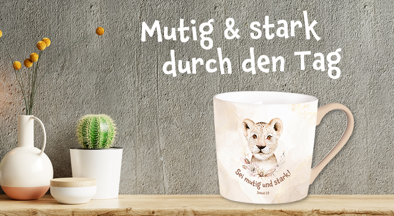 Banner mit Holzbrett, vor einer grauen Wand, auf dem eine Tasse mit Löwen-Motiv drauf ist. Text: "Mutig & stark durch den Tag".