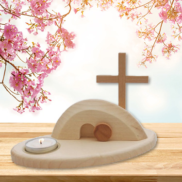 Kleine Osterkrippe 'Jesus ist der Sieger' auf Tisch vor Himmel mit Blütenzweigen