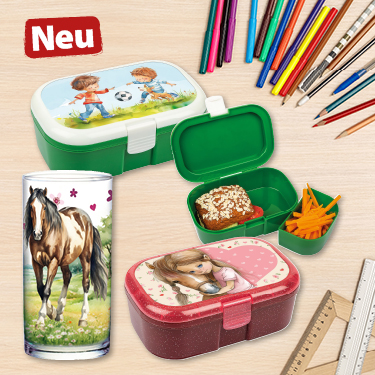 Kinderboxen zum Mitnehmen in Grün und Rosa mit verschiedenen Fächern, gefüllt mit Essen. Daneben Trinkglas mit Pferd, bunte Stifte und Lineal auf Holztisch.