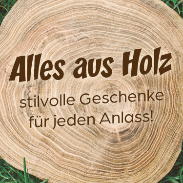 Holzscheibe mit Schriftzug: Alles aus Holz - stilvolle Geschenke für jeden Anlass! auf grünem Gras.