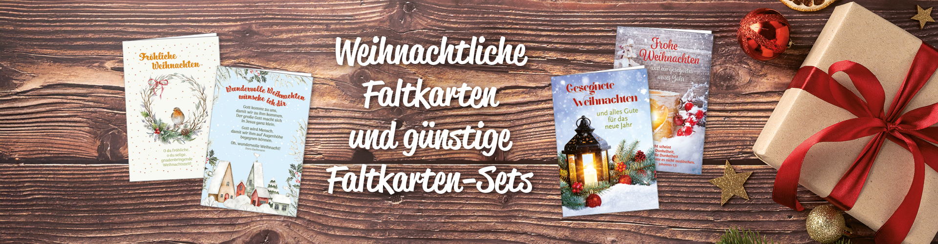 Weihnachtskarten, ein Geschenk und Dekor auf Holzuntergrund. Text: Weihnachtliche Faltkarten und günstige Faltkarten-Sets